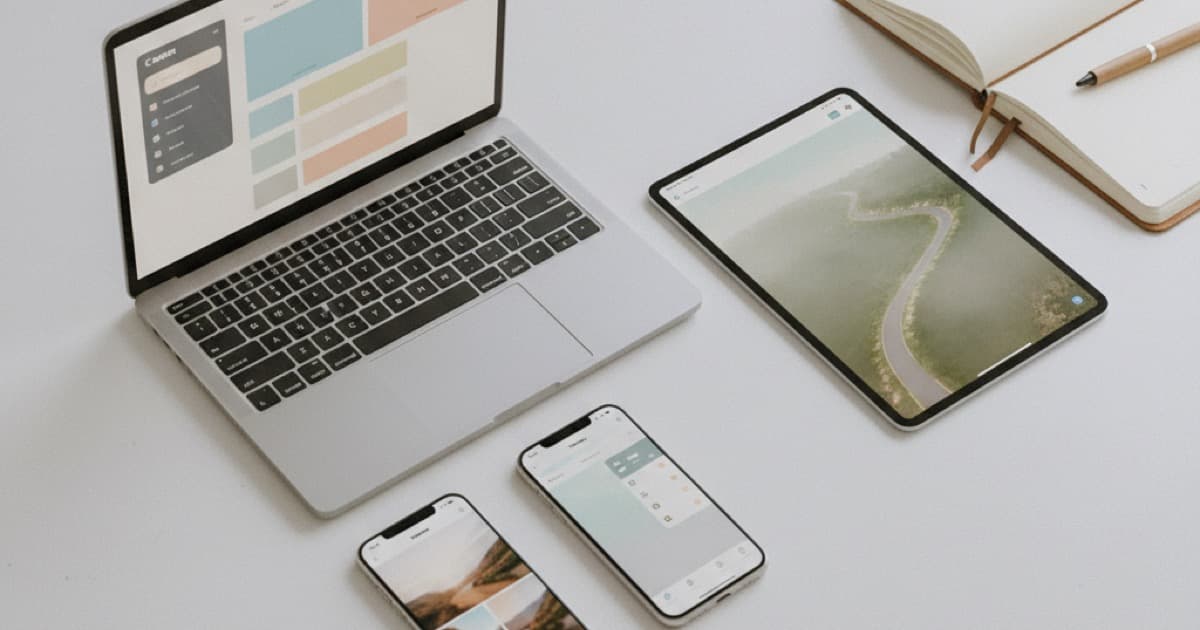Top-down view of a clean desk with laptop, tablet, and smartphones showing different app interfaces